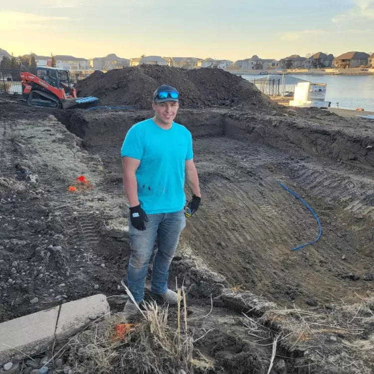 Ryan, the owner of splash pools, standing in front of a hole dug for a pool